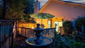 A patio with a fountain, outdoor seating, and a wooden fence. - Family & Pet Friendly Home in Quiet Neighborhood - Close to Beaches & Downtown! (Mount Pleasant)