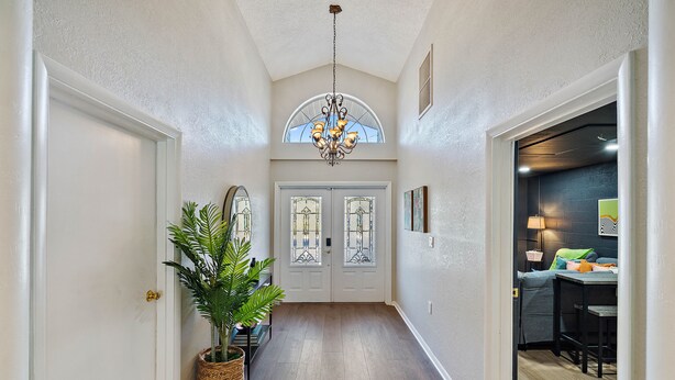 A hallway with a chandelier, double doors with stained glass, and a plant. - Clearwater Game House! Heated Pool, Bowling, Golf! (Largo)