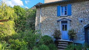 A stone building with a blue door and shutters, surrounded by lush greenery and a clear sky. - Apartment in an old mill in a quiet area. Parc des Baronnies. (Aubres)