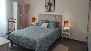 A bedroom with a bed, two bedside tables, a wardrobe, and a painting on the wall. - Apartment in an old mill in a quiet area. Parc des Baronnies. (Aubres)