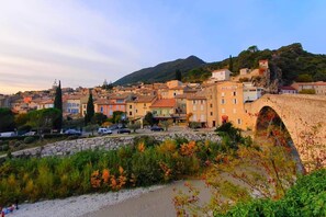 Une ville côtière dotée de bâtiments historiques, d’un pont en pierre et bordée de montagnes.