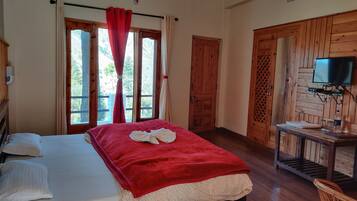 Una habitación con una cama, un escritorio de madera, un televisor y una ventana con cortinas.