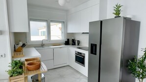 Una cocina moderna con armarios blancos, un refrigerador de acero inoxidable, horno empotrado y una ventana sobre el fregadero.