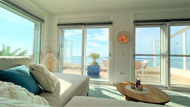 Una habitación amplia con un gran ventanal, un sofá, una mesa y una planta en maceta.