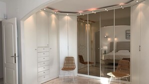 Un dormitorio con cama, armario, espejo y una silla.