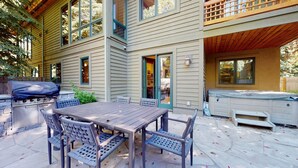 A patio with a wooden table and chairs, a grill, and a hot tub. - Williams Townhome - Luxury Multi-Level with Private Hot Tub (Ketchum)