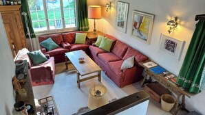A cozy living room with a red sofa, a wooden coffee table, and a window with curtains.