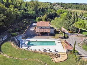 A villa with a swimming pool, surrounded by a garden and a stone wall.