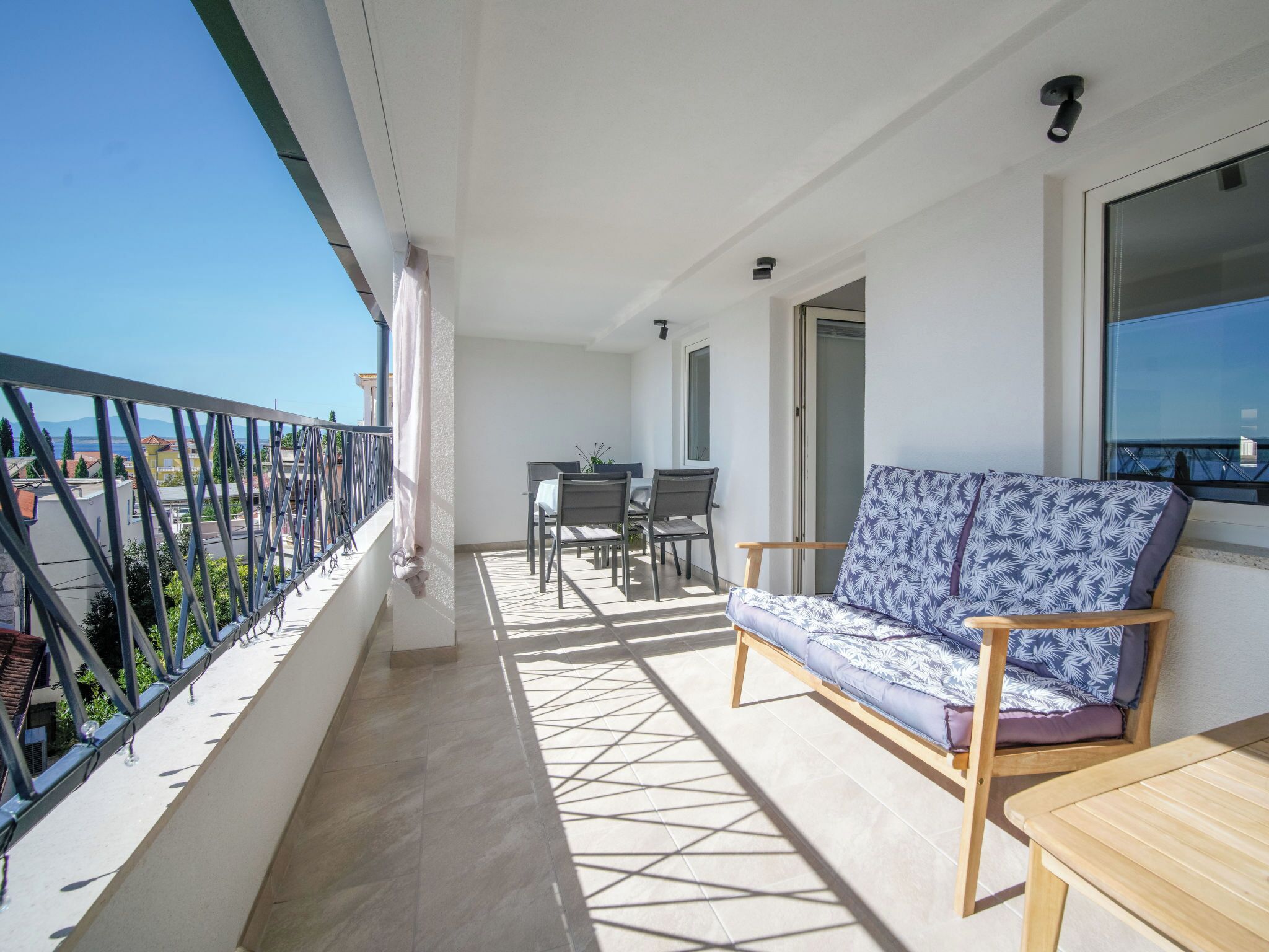 Ein Balkon mit einer Couch, einem Tisch und einem Esstisch.