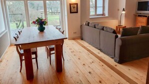 A spacious living area with a wooden dining table, grey sofa, and a television on a wooden cabinet. - Parkblick by Interhome (Wurzen)