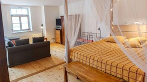 A bedroom with a four-poster bed, a sofa, a TV, and a window. - Parkblick by Interhome (Wurzen)