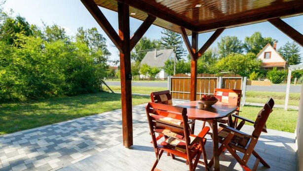 Eine Terrassenausstattung im Freien mit einem Holztisch und -stühlen, umgeben von einer Holzpergola.