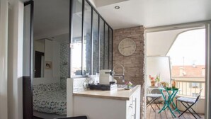 Ein gemütlicher Wohnraum mit Küchenzeile, einem Bett, einer Essecke mit Tisch und Stühlen sowie einem Balkon mit Aussicht.
