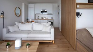 Un espai de vida modern amb un sofà, una taula de centre i una zona de cuina.