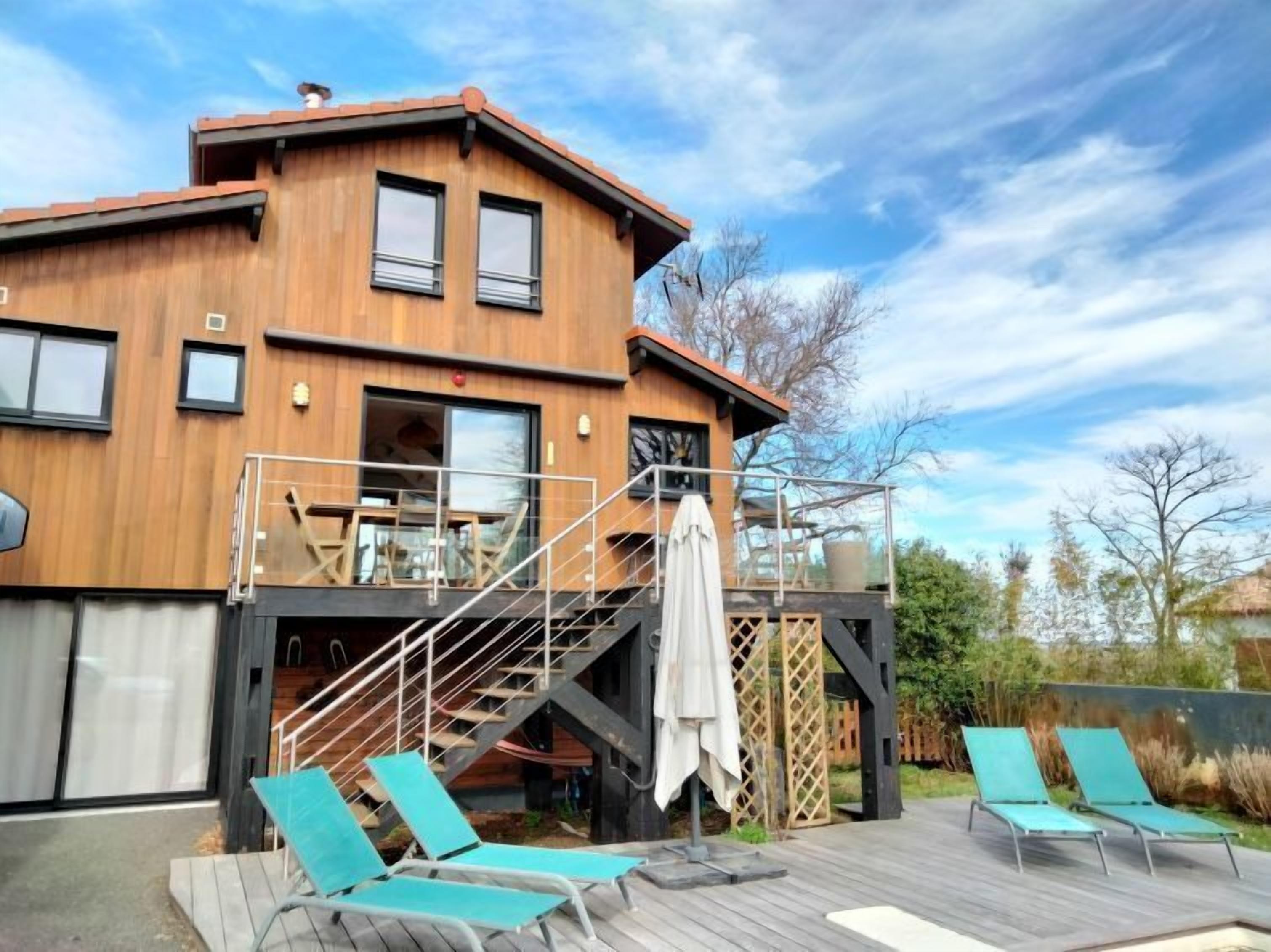 A modern wooden building with a balcony and outdoor seating area.