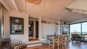 Een ruime woonkamer met een open haard, houten vloeren en een groot raam met uitzicht.