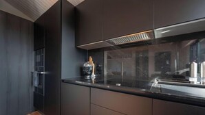 Een moderne keuken met donkere kastjes, een roestvrijstalen afzuigkap en een glazen spatwand.