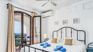 Et soveværelse med seng, balkon og havudsigt samt en aircondition.
