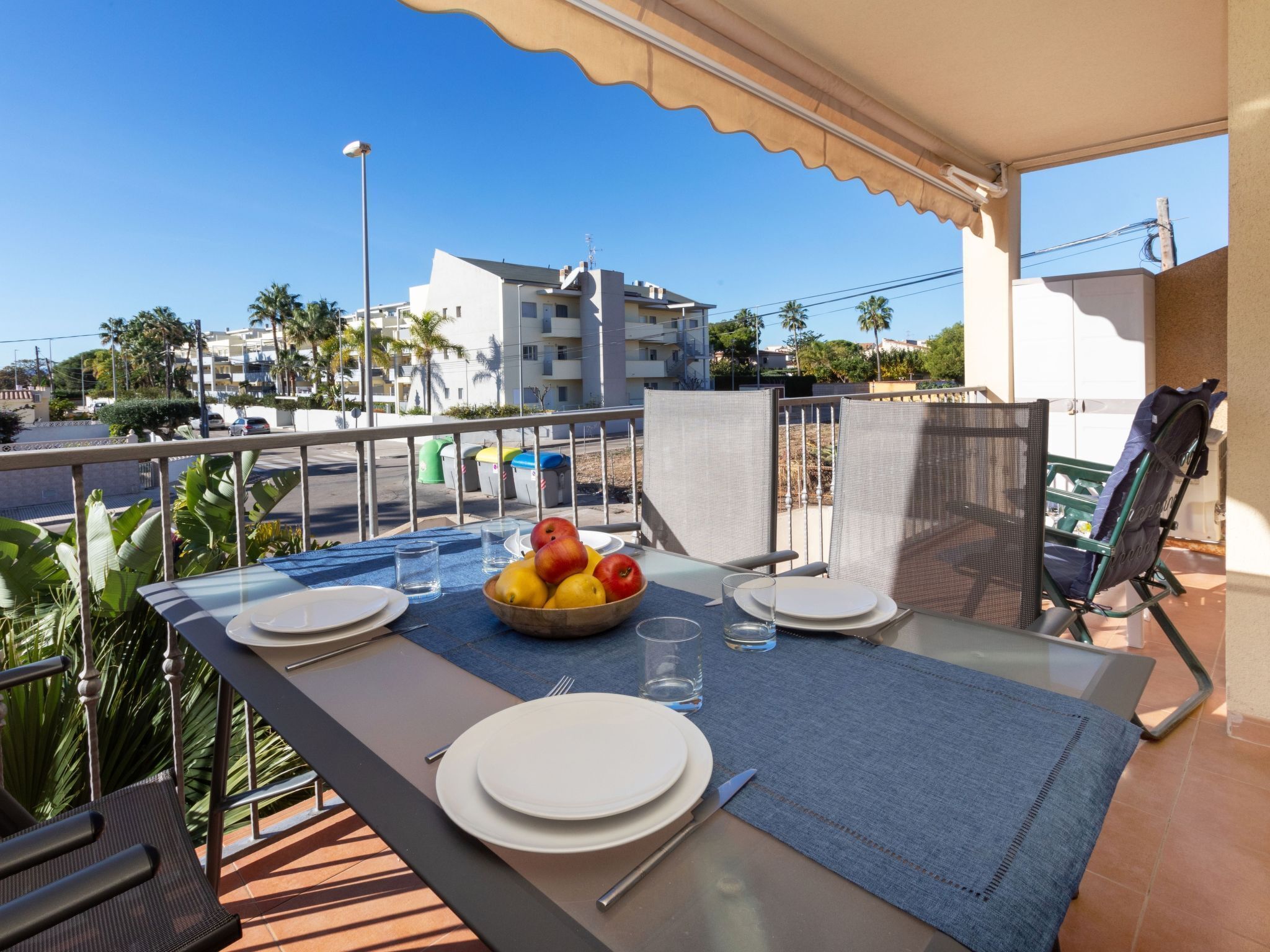 Ein Balkon mit Tisch für zwei Personen, mit Obstschale, Tellern und Besteck.