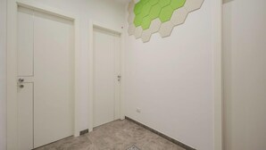 A hallway with three white doors, a green and beige hexagonal wall decoration, and a tiled floor. - Apartment Blu by Interhome (Rapallo)