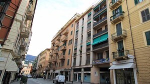 A multi-story building with balconies, a storefront, and a parked van on the street. - Apartment Blu by Interhome (Rapallo)