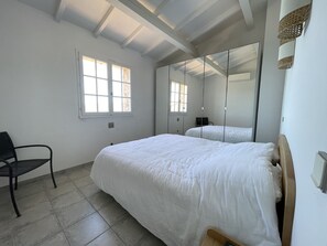 Relax in this serene space with a large bed, a mirror, and a comfortable chair.
