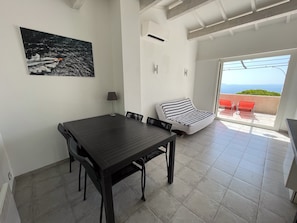 Enjoy a meal at the large table with four chairs, overlooking the sea and green landscape from the balcony.