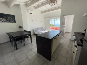 Una cucina moderna con isola centrale, zona pranzo con tavolo e sedie e vista sull'esterno.