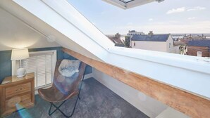 A room with a skylight, a chair, a small table, and a radiator. - Host & Stay | Mumbles Cottage (Whitby)