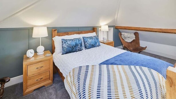 A bedroom with a bed, a nightstand, a lamp, and a chair. - Host & Stay | Mumbles Cottage (Whitby)