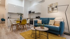 Ein modernes Wohnzimmer mit einem blauen Sofa, gelben Sesseln, einem kleinen Couchtisch und einer Stehlampe.