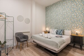 A bedroom with a bed, a chair, a radiator, and a wall with a leaf pattern.