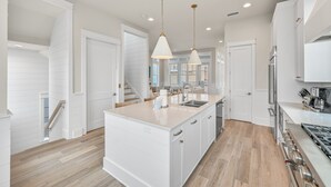 A modern kitchen with white cabinetry, a central island, stainless steel appliances, and pendant lighting. - Steps From Beach Access + Private Pool- Sunset Lounge by Royal Destinations (Santa Rosa Beach)