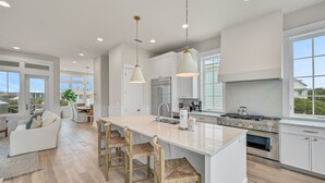 A modern kitchen with a large island, stainless steel appliances, and a view of the outdoors. - Steps From Beach Access + Private Pool- Sunset Lounge by Royal Destinations (Santa Rosa Beach)