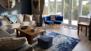 A cozy living room with a sofa, two blue chairs, a coffee table, and a rug. - Willows Worthing 4 bed With ev Charger & sea Views (Worthing)