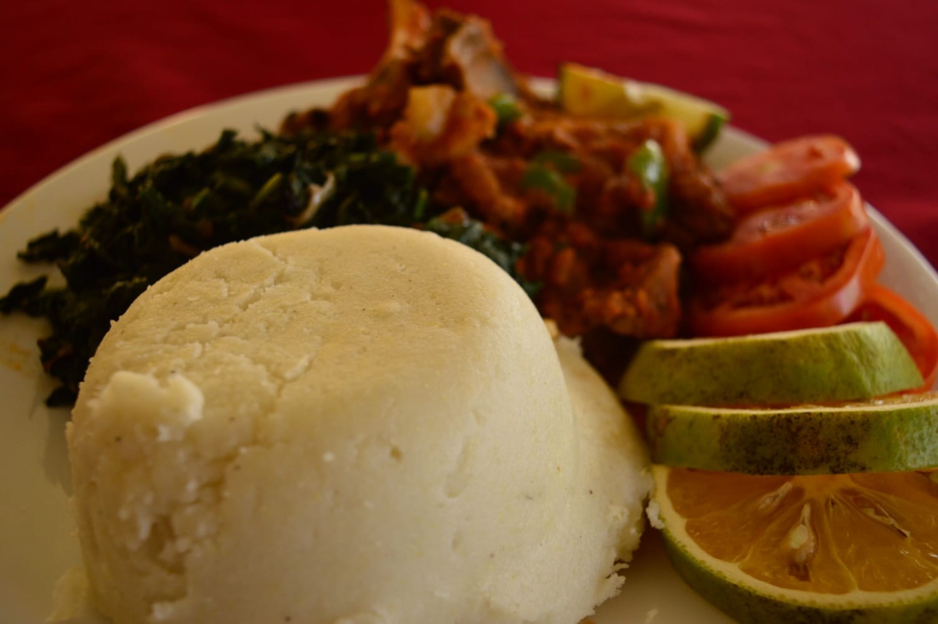 A plate with white rice, greens, sliced tomatoes, and a lime half.