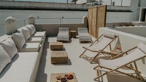 A rooftop terrace with white cushioned seating, wicker lounge chairs, and a woven partition. - EntreArcos Casa Eco-Boutique (Vejer de la Frontera)