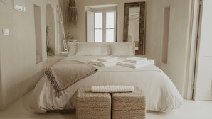 A bedroom with a large bed, two bedside tables, a window, and a mirror. - EntreArcos Casa Eco-Boutique (Vejer de la Frontera)