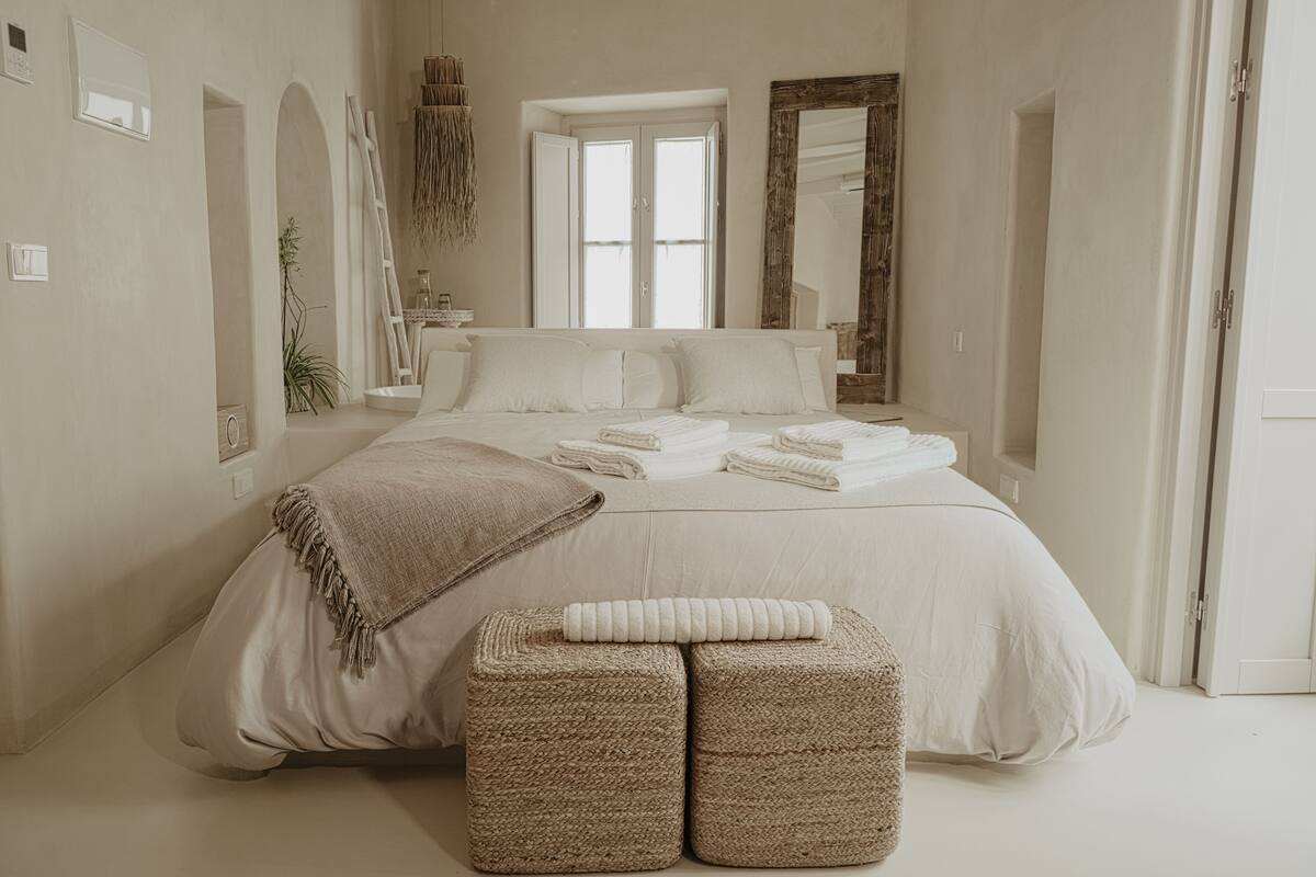 Un dormitorio con una cama grande, dos mesitas de noche, una ventana y un espejo.