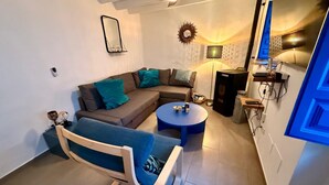 A modern living room with a sofa, a blue armchair, a coffee table, and a TV. - Mi Sueño Azul Torrox Pueblo (Torrox)