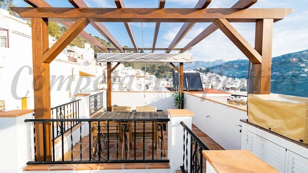 A rooftop terrace with a wooden pergola, a table, chairs, and a view of the city and mountains. - Mi Sueño Azul Torrox Pueblo (Torrox)