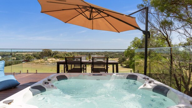 A hot tub with a table and chairs, an umbrella, and a view of the landscape. - Moonah Link Views, Spa, Sunset, Linen, Wi-Fi, private and serene (Fingal)