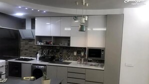 Une cuisine moderne équipée d’une cuisinière, d’un four à micro-ondes et d’un évier intégrés. On y trouve des placards, un plan de travail et un luminaire suspendu.