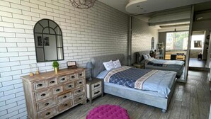 Une chambre à coucher avec un grand lit, une commode, un miroir et un pouf rouge.