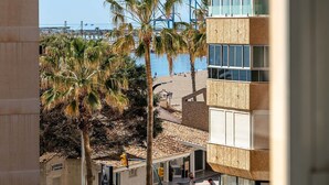 A view of a beach with palm trees and a building with large windows.