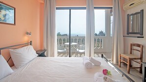 Een hotelkamer met een bed, een stoel, een tafel en een balkon met uitzicht.