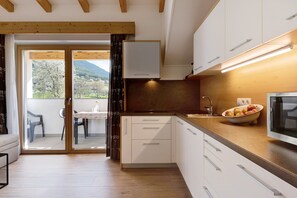 Cozinha moderna com armários brancos, bancada de madeira e uma tigela de frutas.