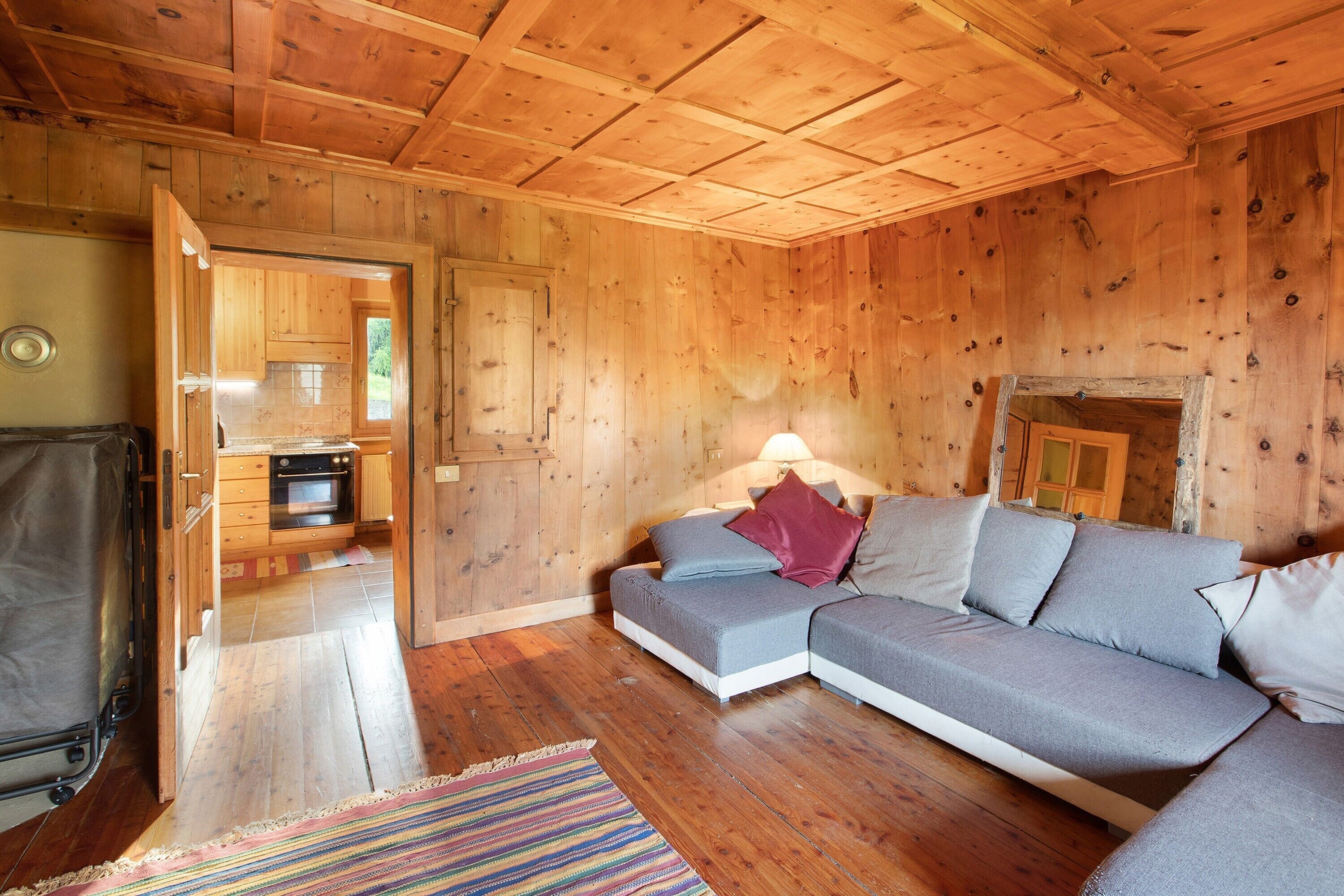 A wooden interior with a sofa, a fireplace, and a kitchen area.