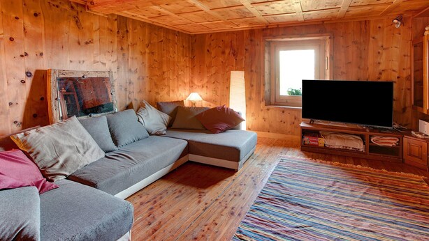 Ein Holzblockbau-Innenraum mit einer Couch, einem Fernseher und einem Fenster.