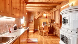 Eine Holz Küche mit eingebautem Herd, einer Mikrowelle und einem Essbereich mit Holztischen und -stühlen.